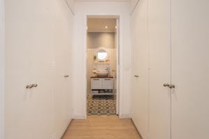 Elegant narrow hallway with white closets leading to a stylish bathroom featuring modern decor in Bogotá.