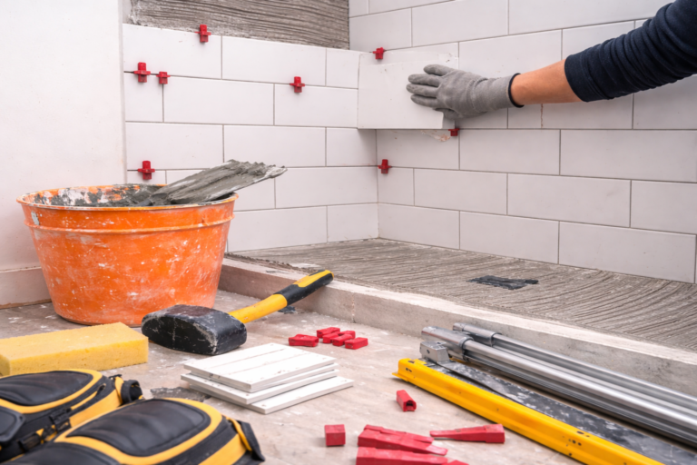 Bathroom retiling in progress with freshly installed ceramic wall tiles, exposed grout lines, and renovation tools in a modern bathroom setting.